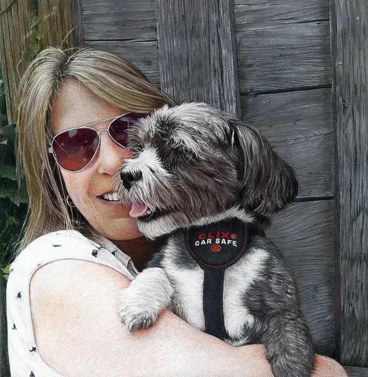 Woman in sunglasses holding a small black-and-white dog in a harness against a wooden wall
