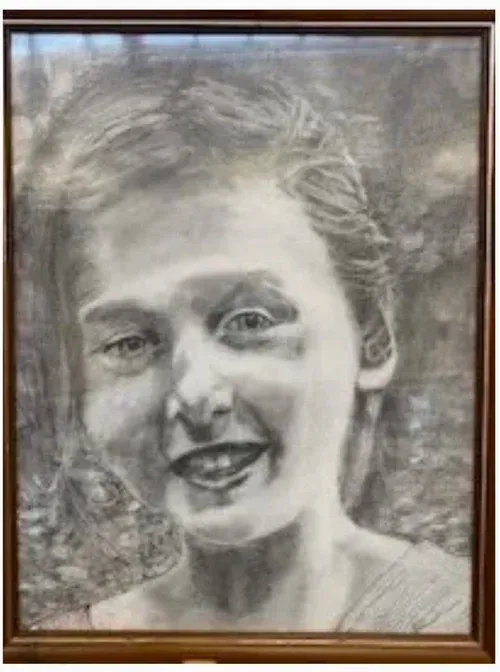 Charcoal portrait of a smiling person in a wooden frame, with a soft gray background.