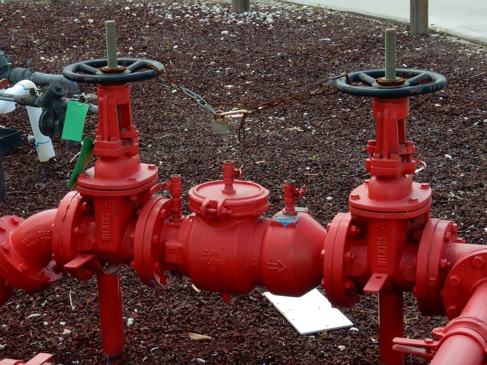Two Red Industrial Gate Valves Connected by a Central Check Valve — Dunnerite Plumbing in Mount Peter, QLD