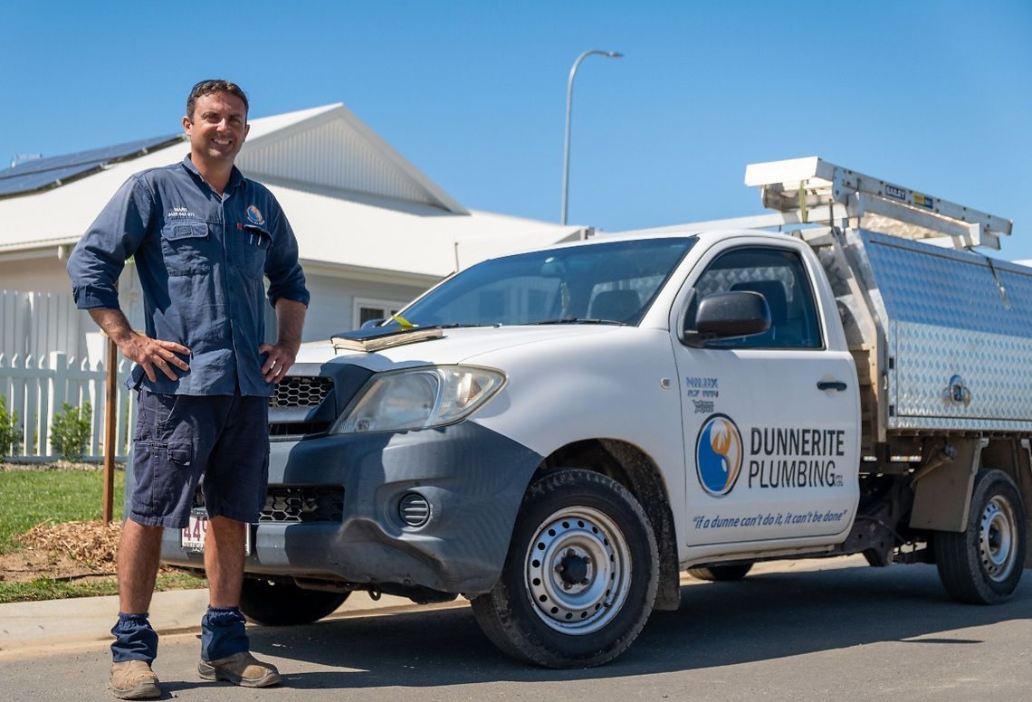 A Person Standing Next to a White Service Truck — Dunnerite Plumbing in Mount Peter, QLD