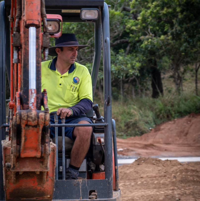 A Person in a High-visibility Polo Shirt Holds a Printed Construction Plan — Dunnerite Plumbing in Mount Peter, QLD