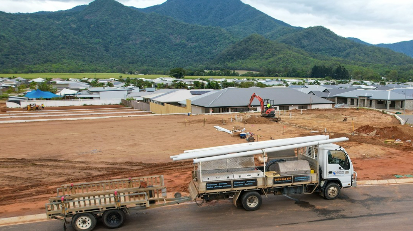 A truck carrying PVC pipes with a trailer attachment is in front of an excavated worksite. — Dunnerite Plumbing in Mount Peter, QLD
