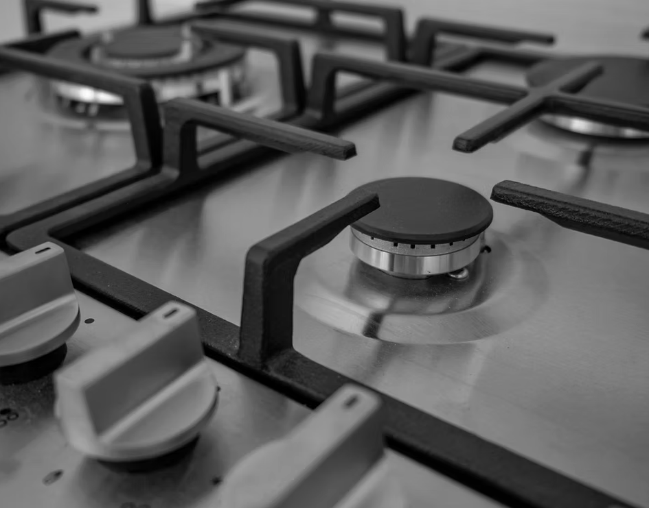 Close-up of a stainless steel gas stovetop with black burner grates and control knobs — Dunnerite Plumbing in Mount Peter, QLD