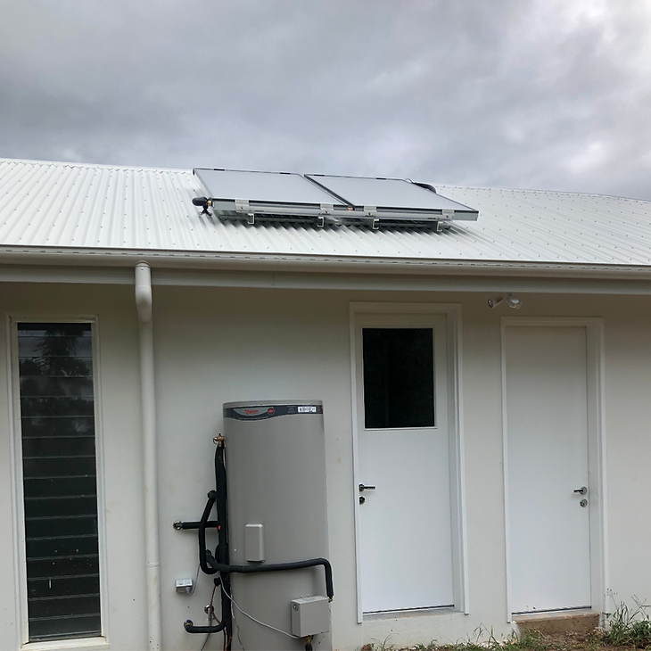 White house exterior with solar panels on the roof and an outdoor utility unit by the wall — Dunnerite Plumbing in Edmonton, QLD