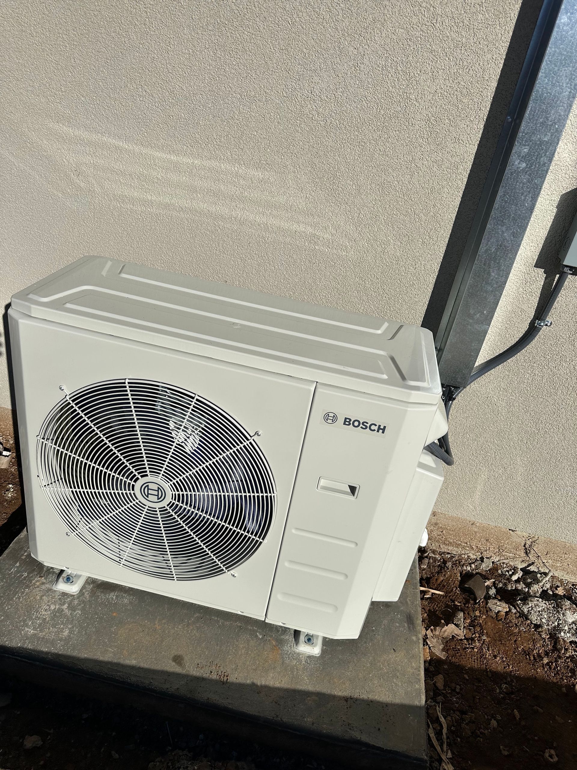 A white air conditioner is sitting on top of a concrete block.
