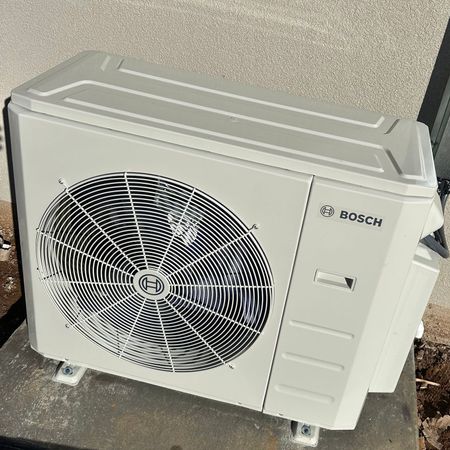 A white bosch air conditioner is sitting on a concrete surface.