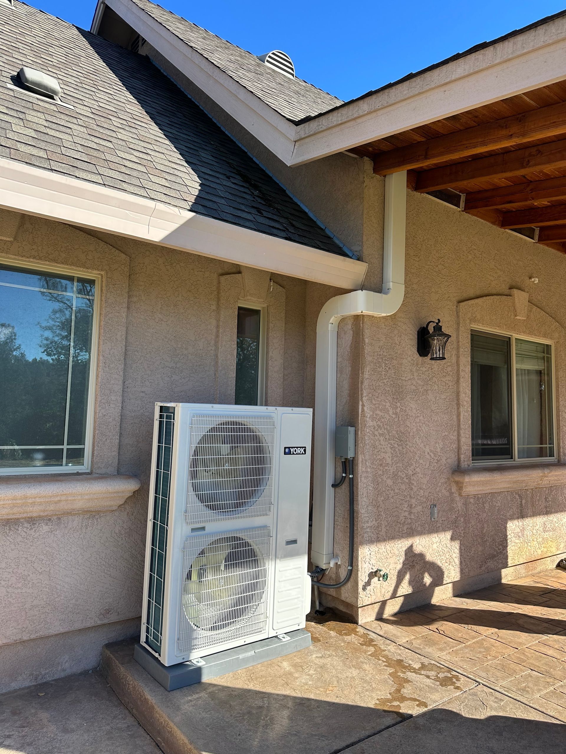A large air conditioner is installed on the side of a house.