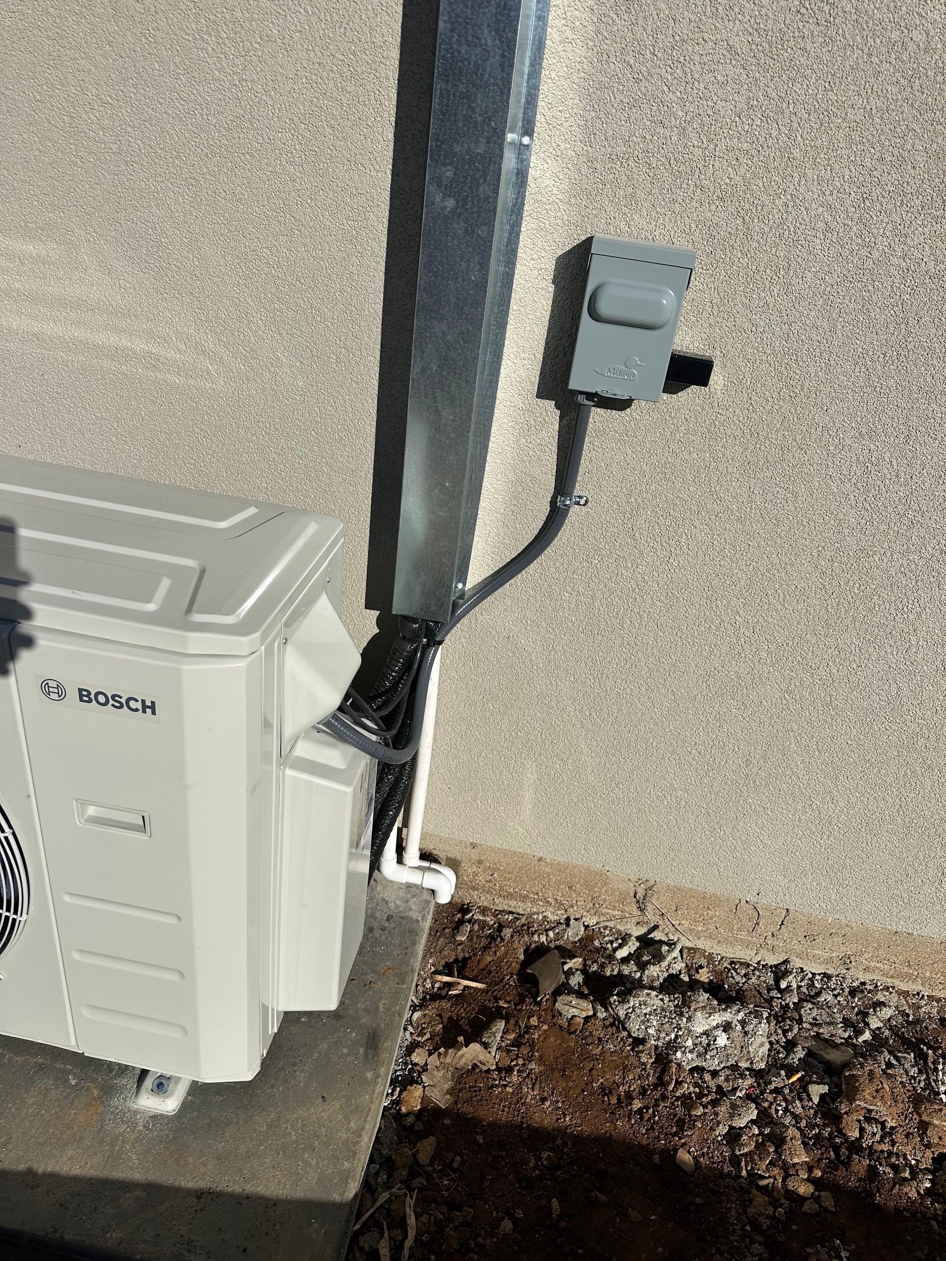 A white air conditioner is sitting on the side of a building.