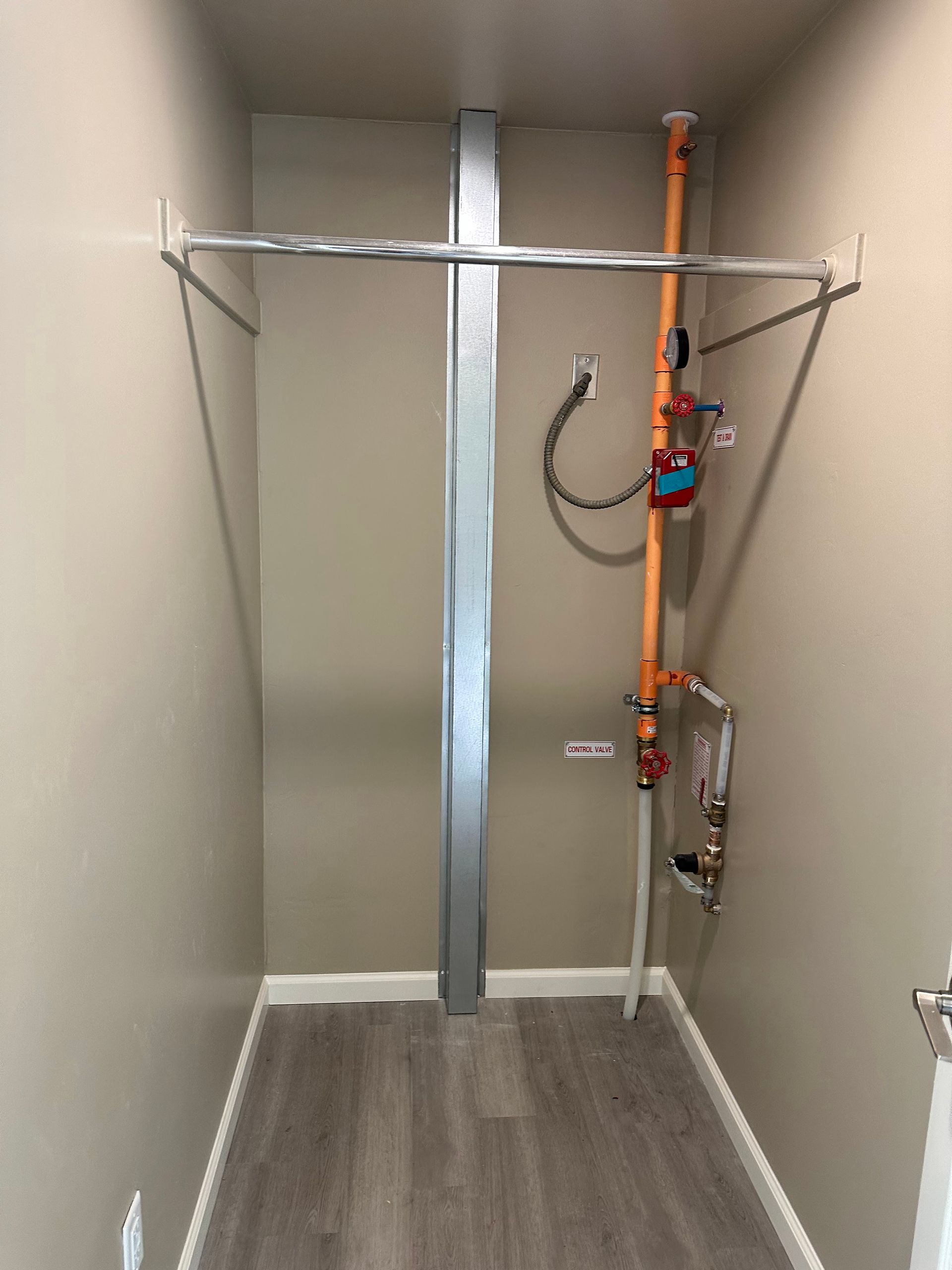 A closet with a pipe hanging from the ceiling.