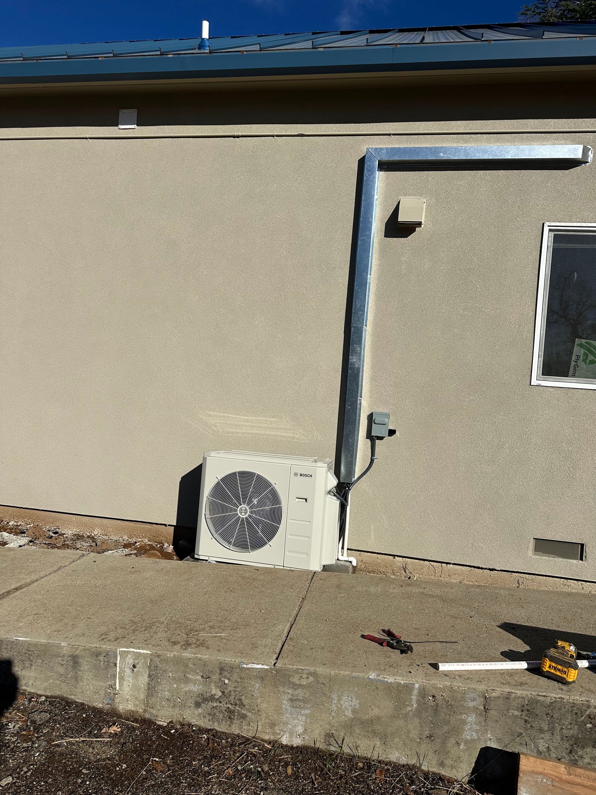 A white air conditioner is sitting on the sidewalk next to a building.