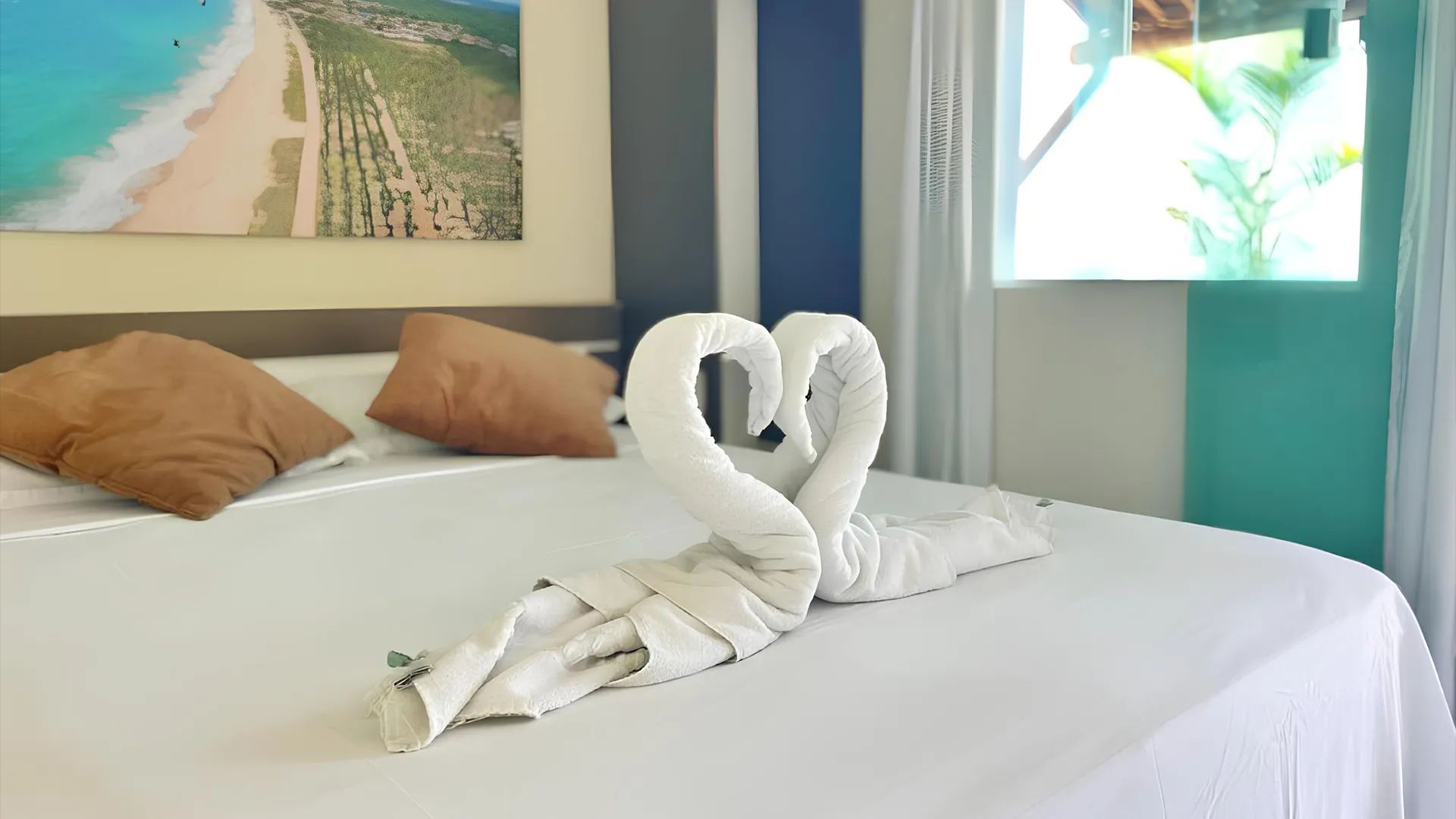 Uma cama com duas toalhas em forma de cisnes.