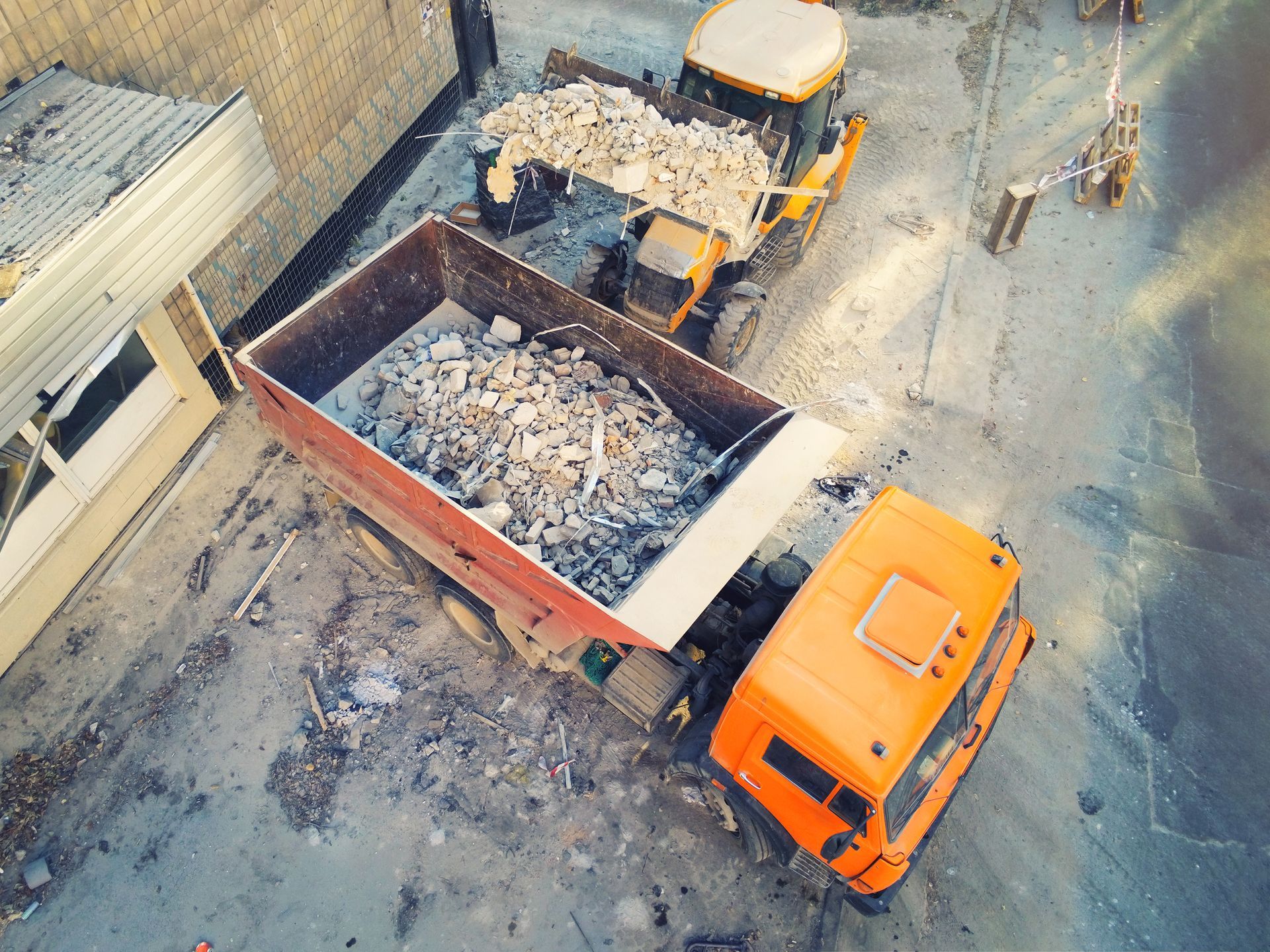 An aerial view of a dump truck filled with rocks on a construction site.