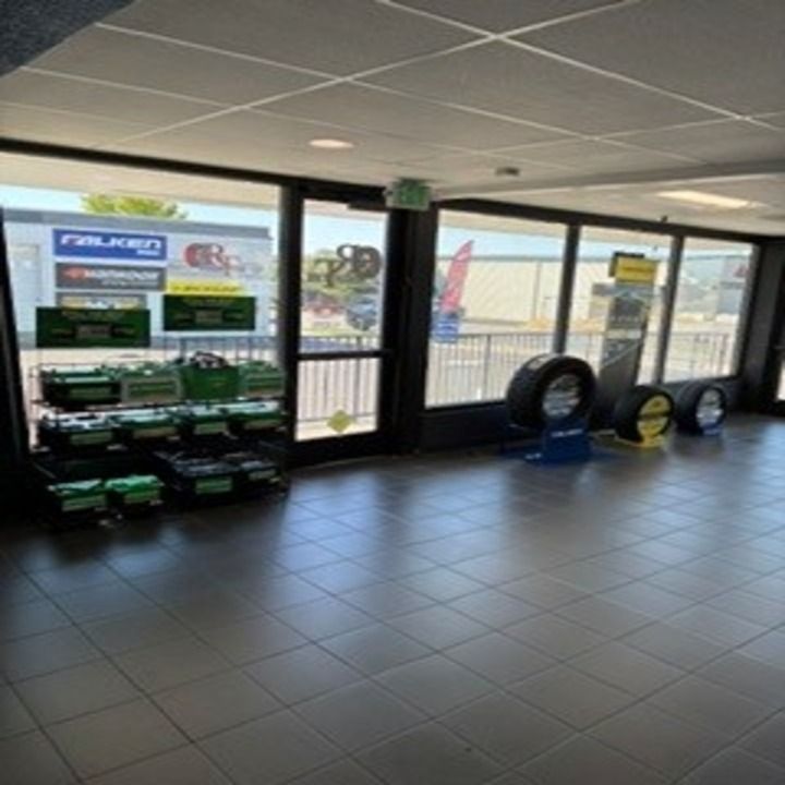Interior of a car dealership showroom with tiled floor, display shelves, and tires by large front windows. Interior of a car dealership showroom with tiled floor, display shelves, and tires by large front windows.