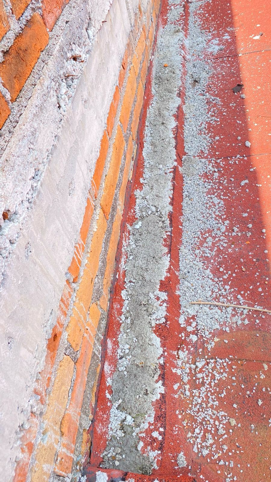 Primer plano de un pavimento pintado de naranja y gris, desgastado por el tiempo, con franjas descascaradas y grietas.