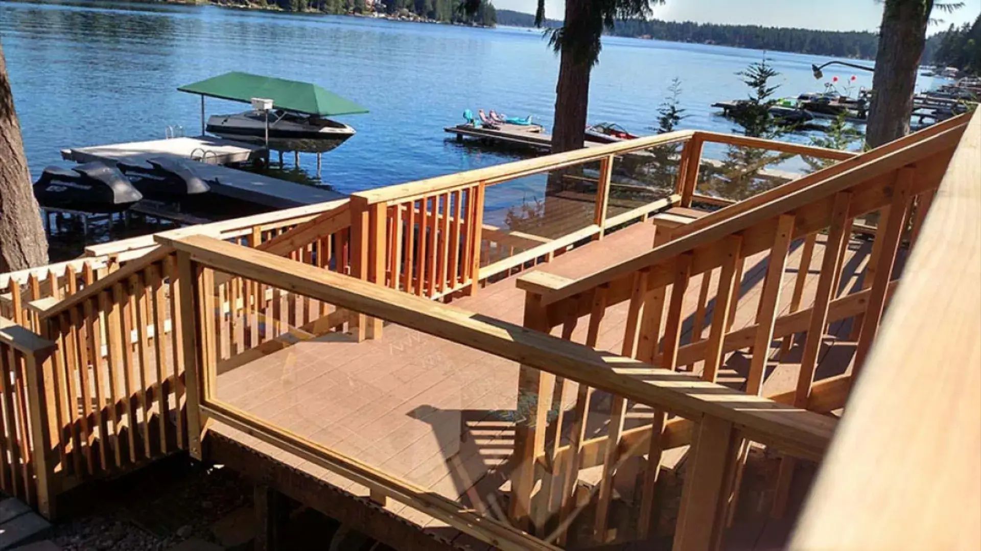 Wooden staircase and dock overlooking a calm lake with boats and trees in the background