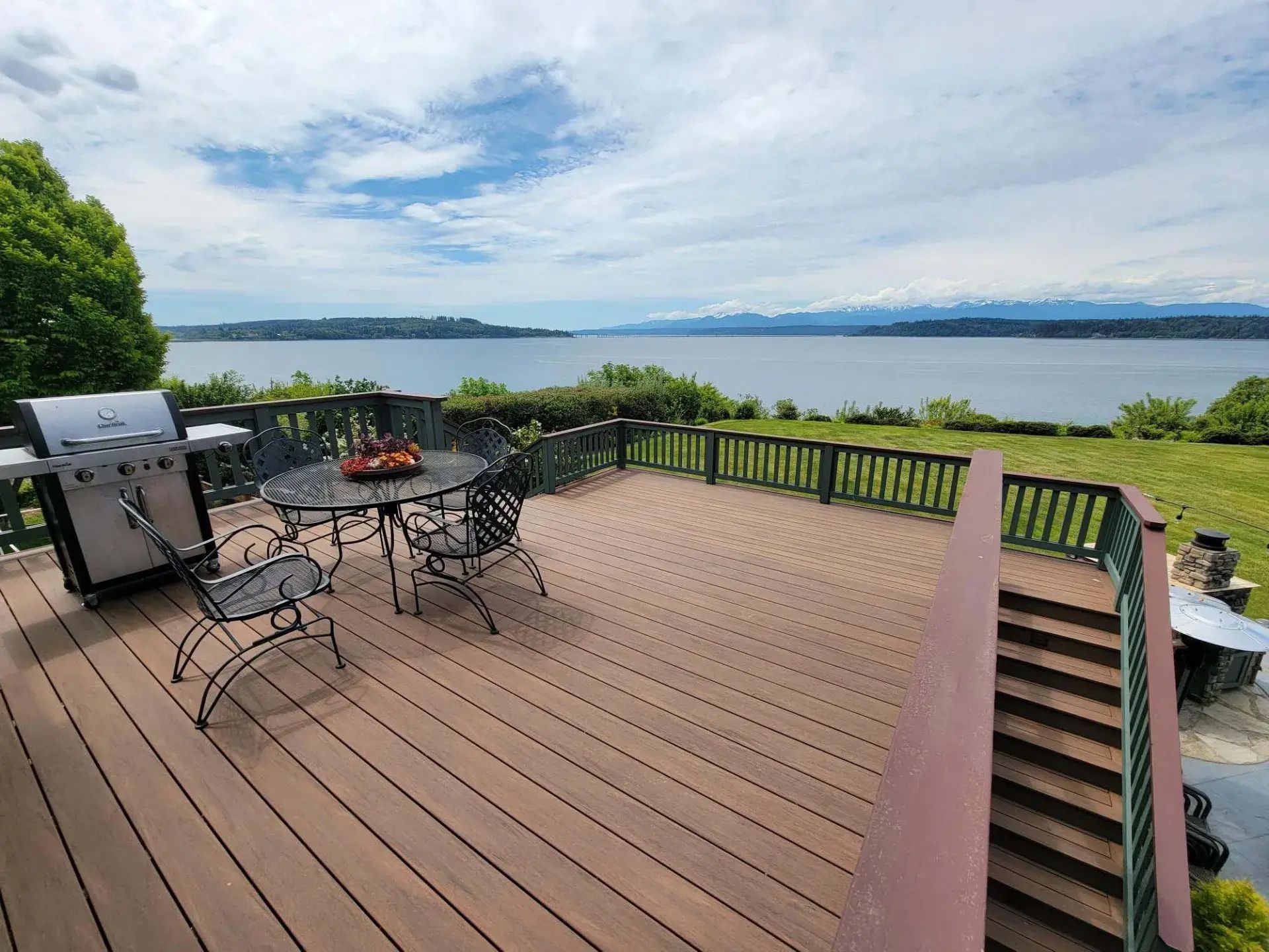 Deck patio with table and chairs overlooking a calm lake and cloudy sky