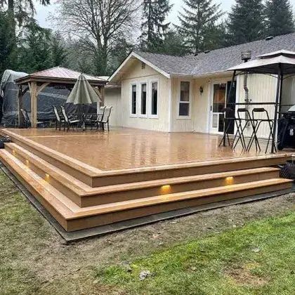 Wooden backyard deck with steps, umbrella, and patio furniture beside a beige house