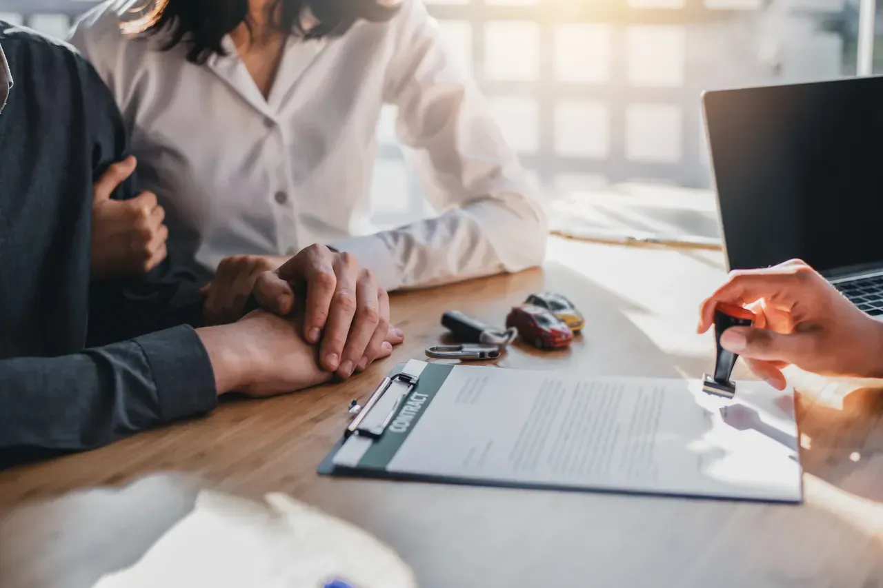 A Man And A Woman Are Sitting At A Table With A Clipboard And A Laptop — Brown & Co Finance in Toowoomba, QLD