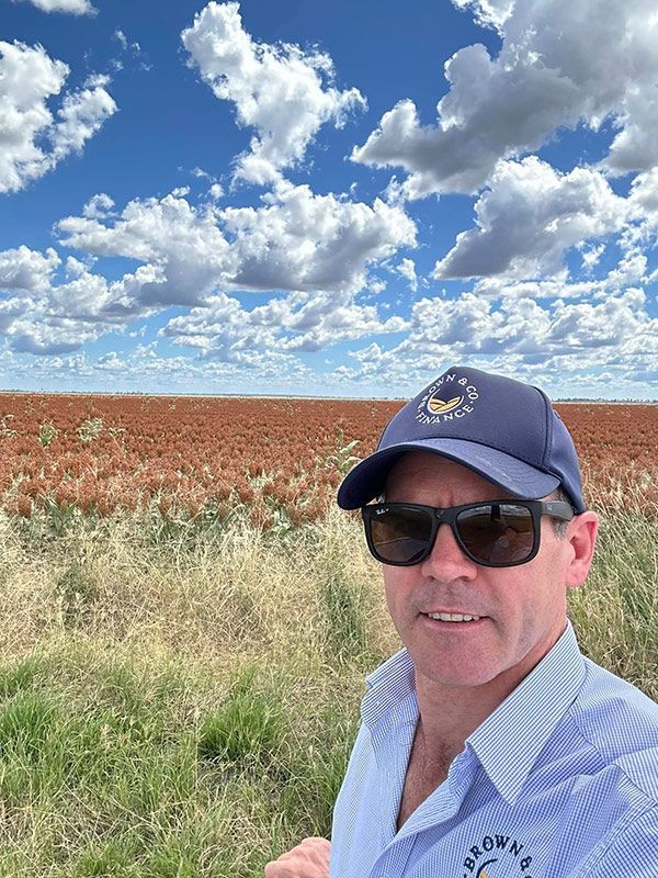 A Man Wearing Sunglasses And A Hat Is Standing In A Field — Brown & Co Finance in Toowoomba, QLD