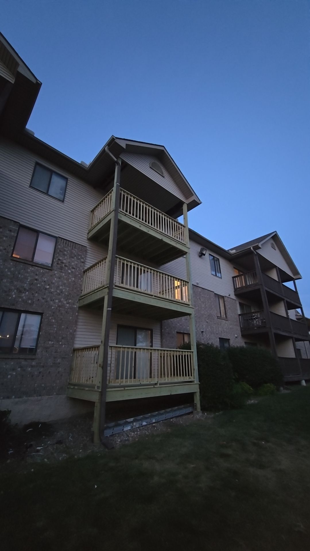 Multi-story apartment building with wooden balconies; evening sky.