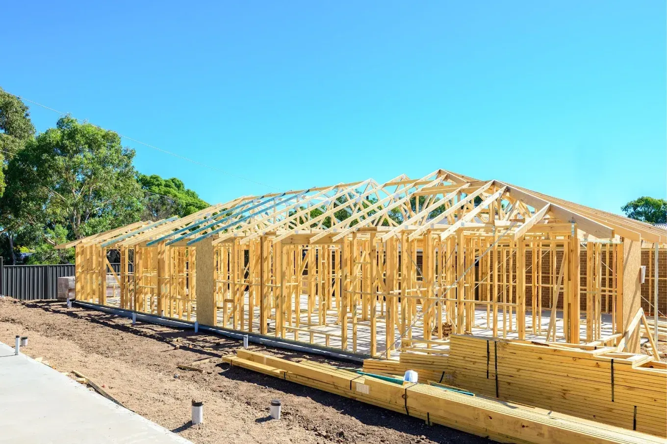 Wooden house frame under construction against a blue sky.