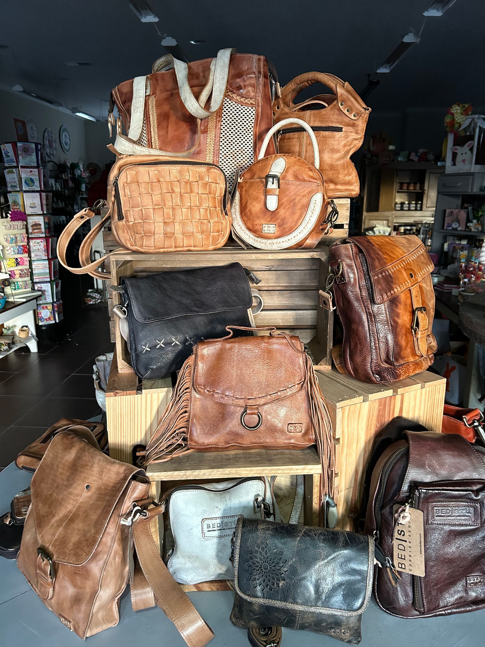 A bunch of leather bags are stacked on top of each other in a store.