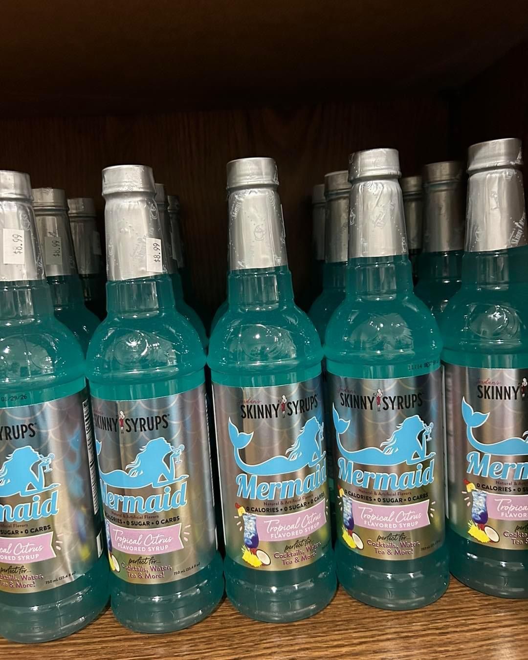 A row of bottles of blue liquid with a mermaid on the label.