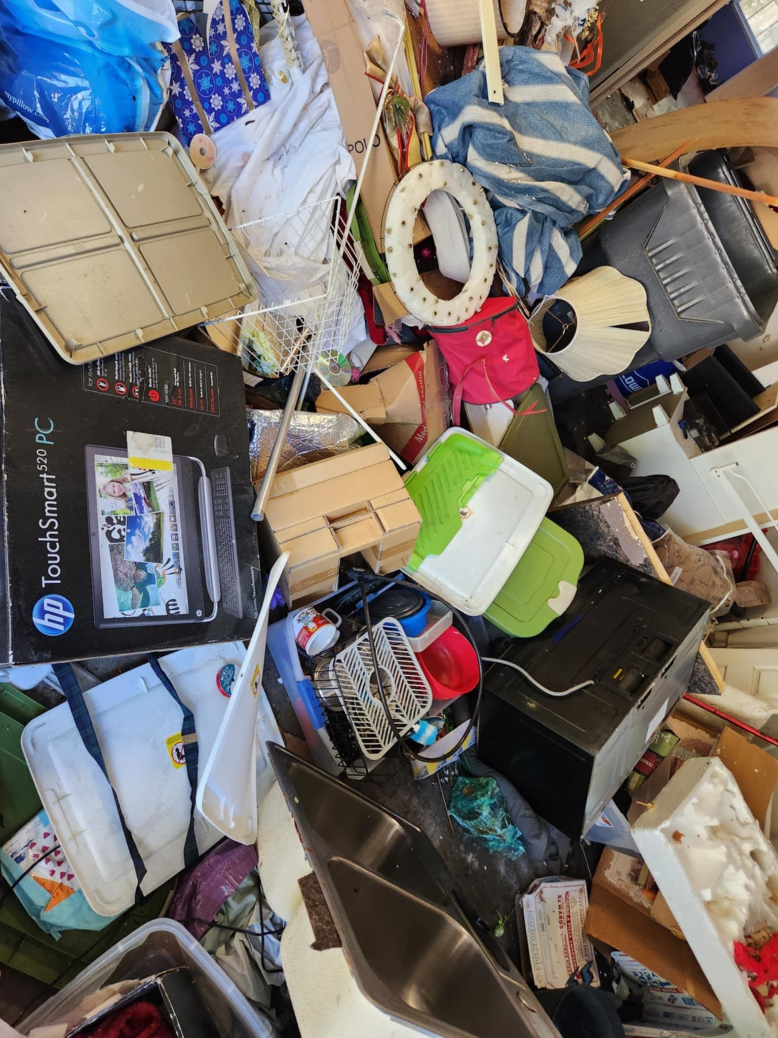 Cluttered pile of assorted boxes, cables, bags, and electronics on a messy floor.