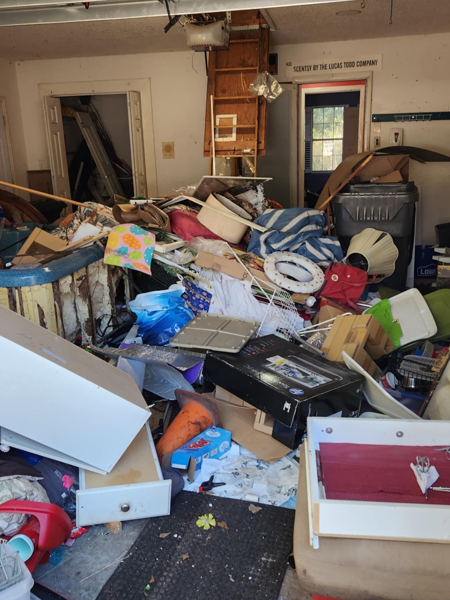 Cluttered room filled with piled debris, boxes, and damaged furniture after severe damage.