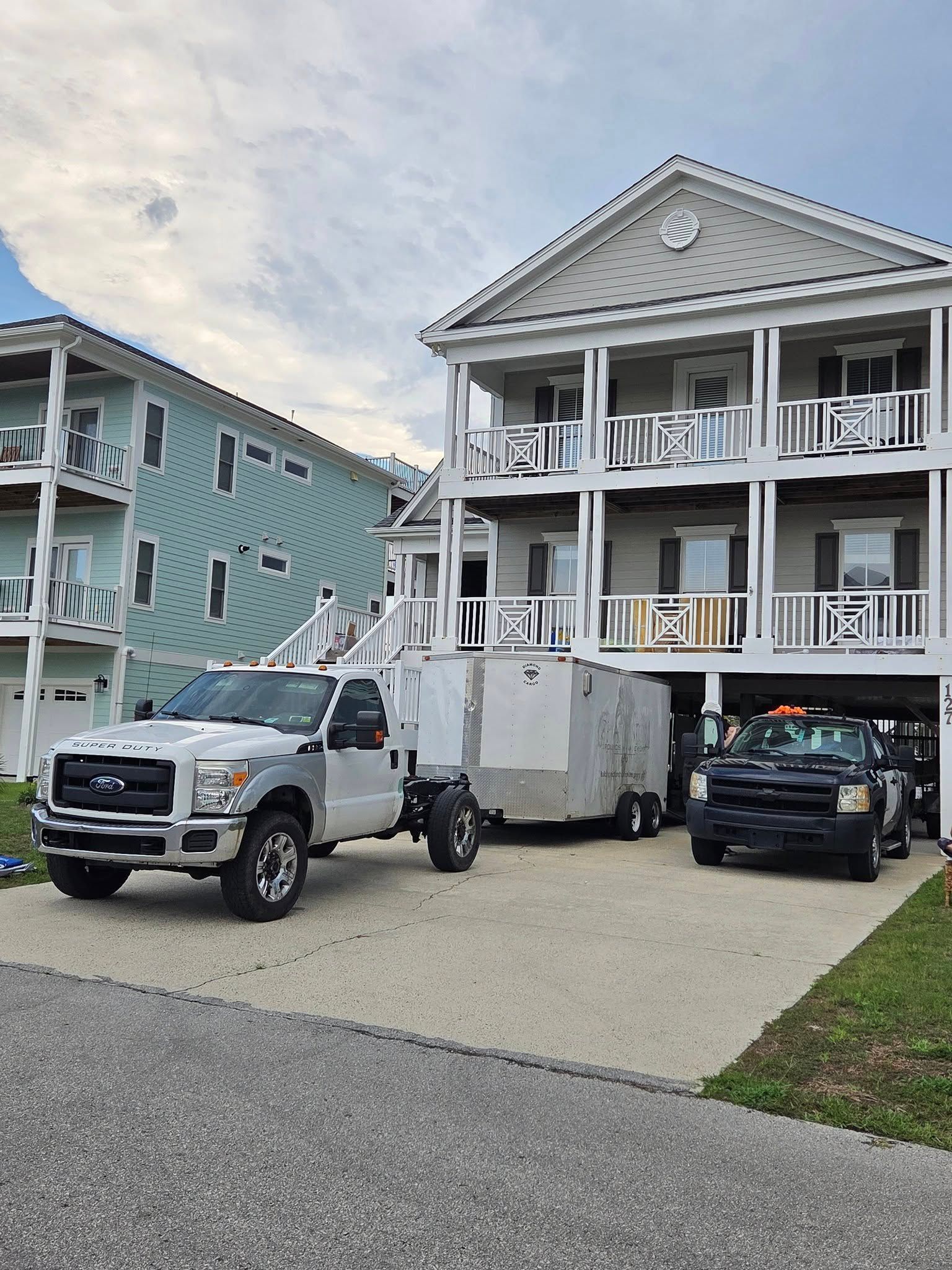 Two-story beach house with parked truck and SUV in the driveway on a cloudy day