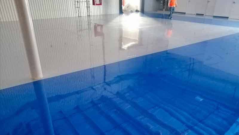 Un suelo brillante que pasa del gris de un lado al azul intenso y reflectante del otro, en el interior de un gran almacén.