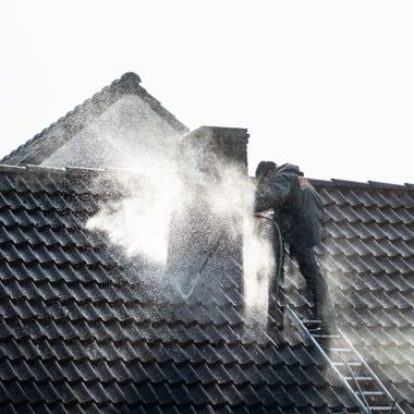 Firefighter spraying water on a smoking roof to extinguish a blaze