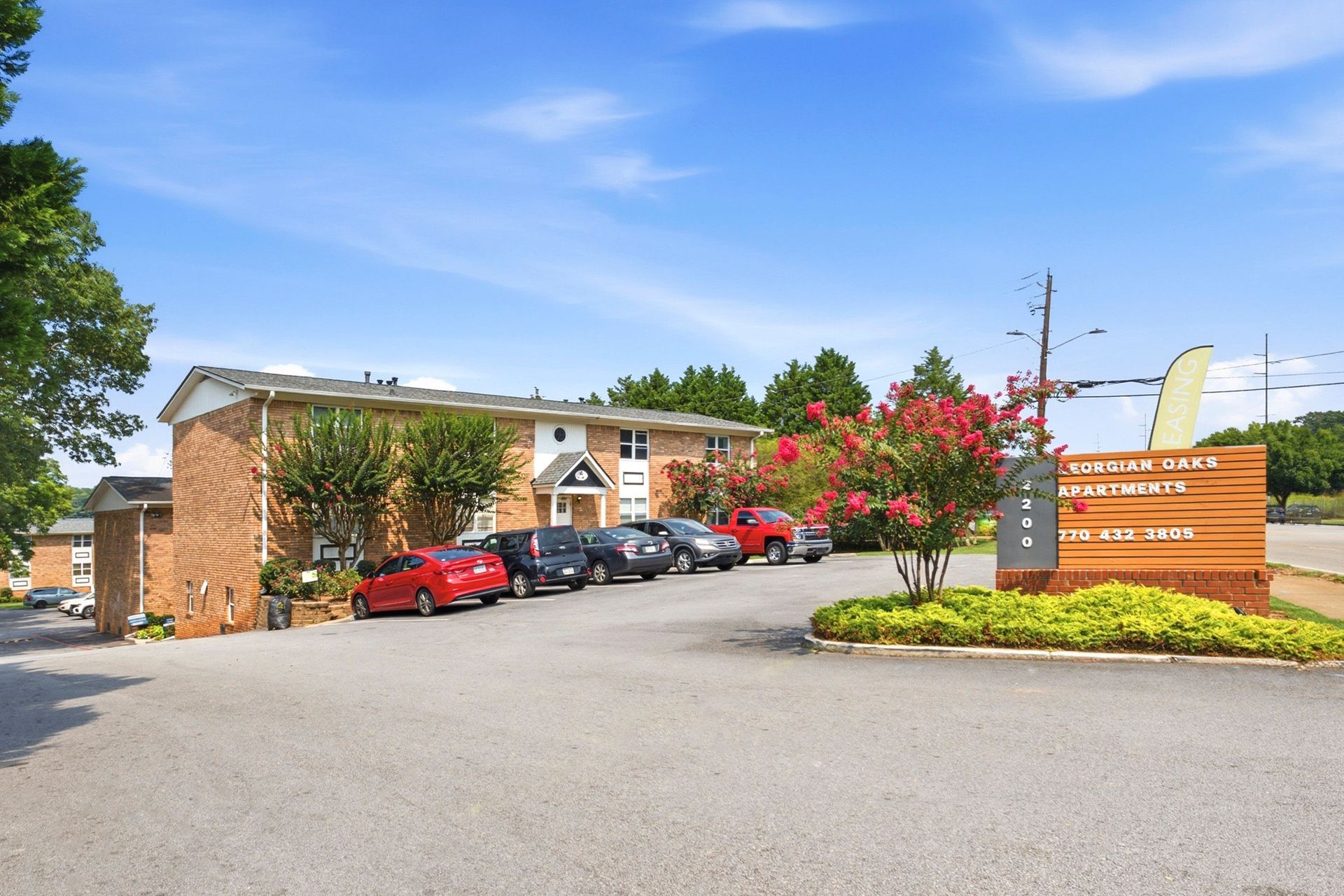 Motel parking lot with red cars, brick building, and a large roadside sign under a blue sky