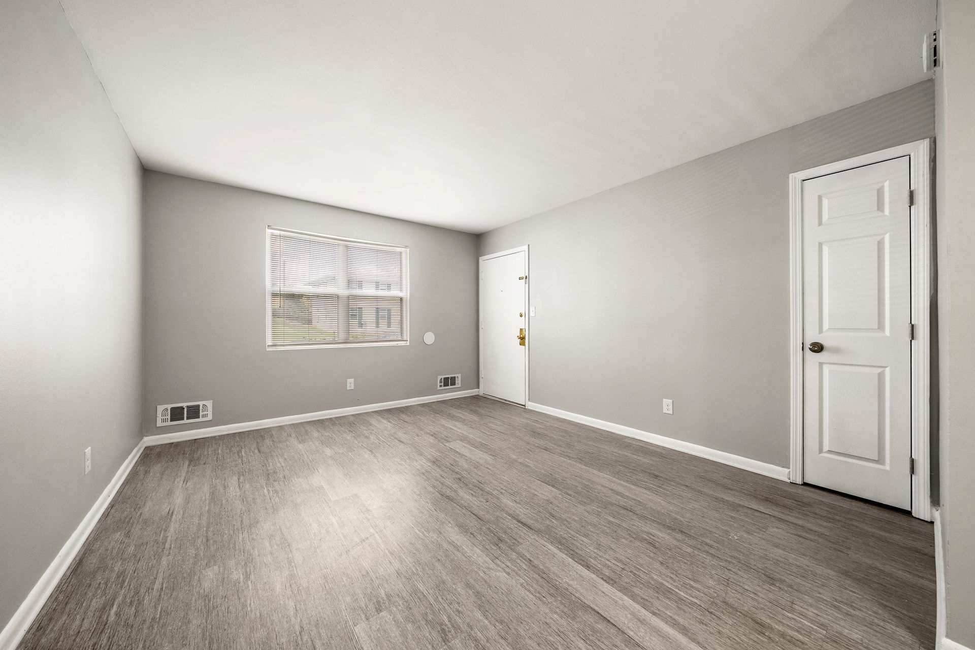 Empty gray bedroom with carpet, window, and white closet doors