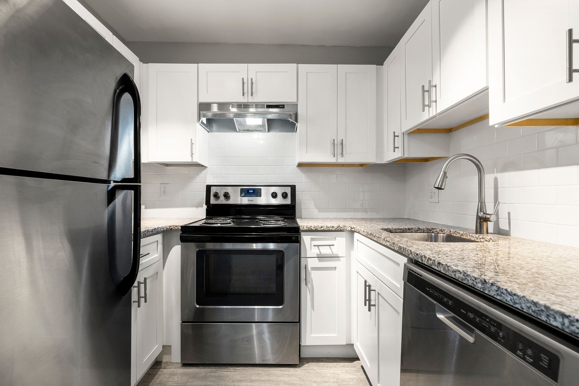 Modern kitchen with stainless steel appliances, white cabinets, and granite countertops