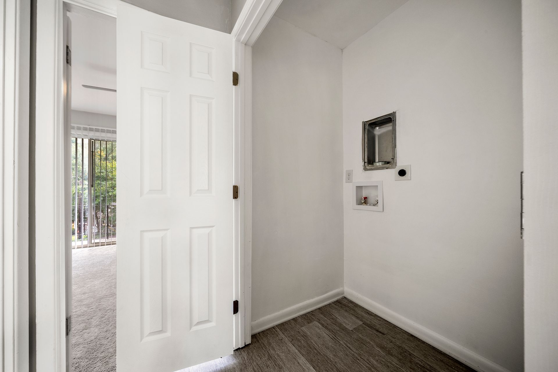 Empty white entryway with open front door and a wall-mounted thermostat panel