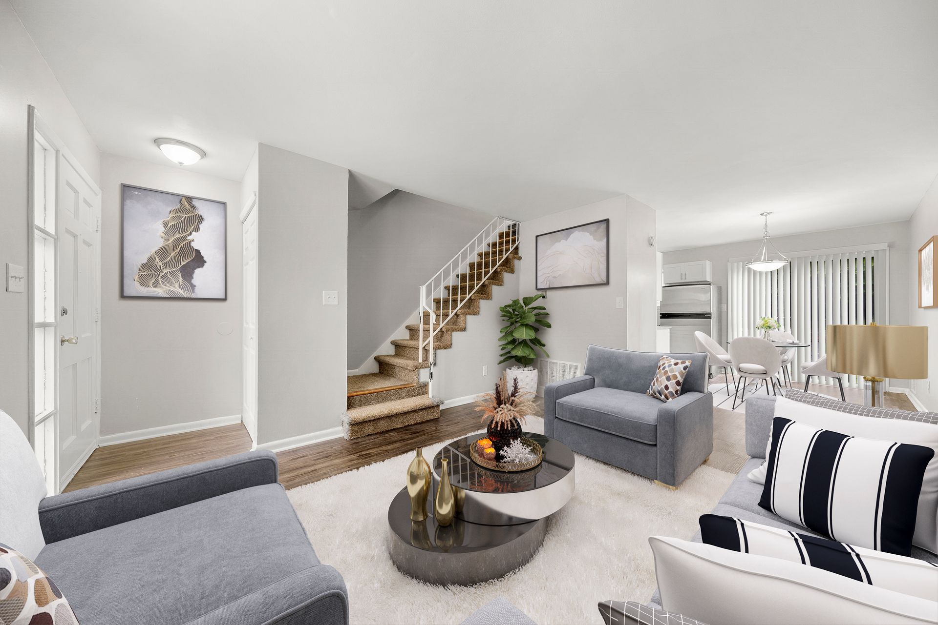 Bright modern living room with gray sofas, round coffee table, staircase, and large windows