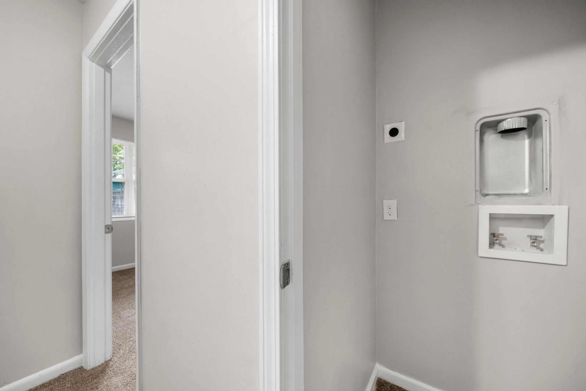 Empty hallway with white walls, doorway, and wall-mounted thermostat and utility panel