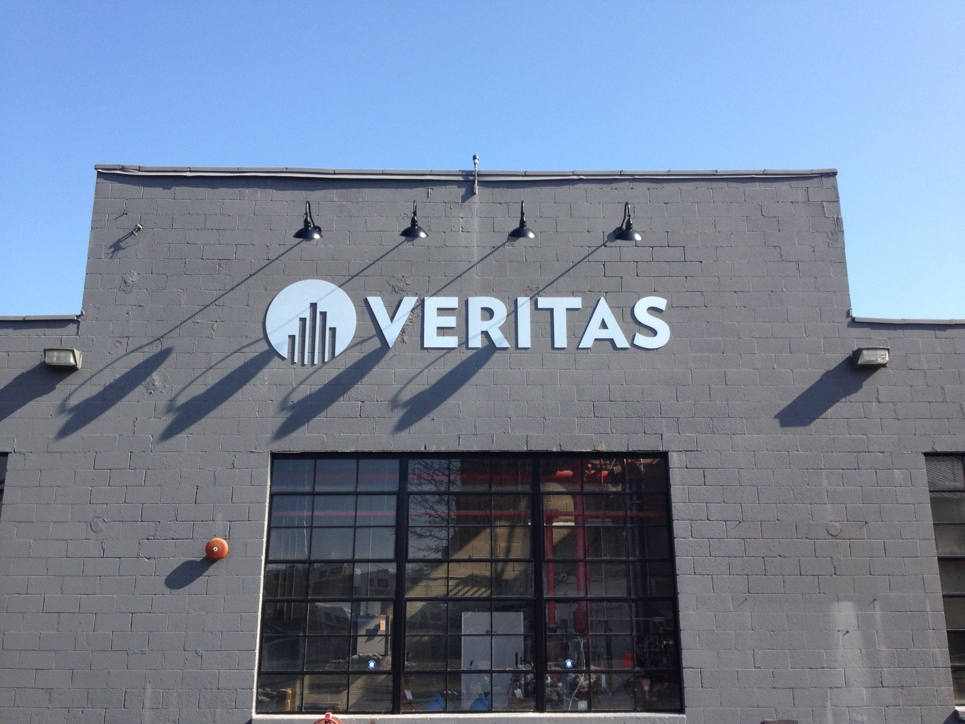 VERITAS sign on a gray brick building under a clear blue sky