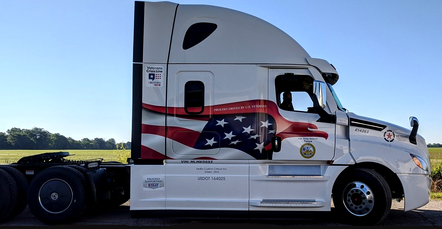 White semi-truck tractor with an American flag graphic, parked in profile outdoors.