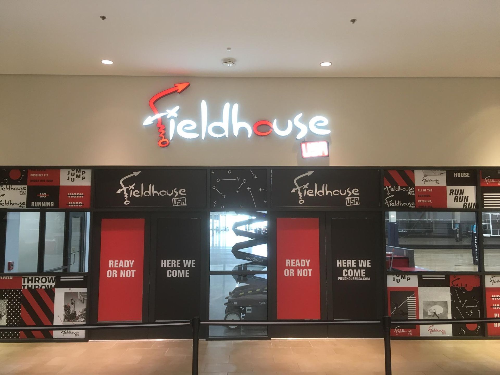 Storefront with “Fieldhouse” neon sign and menu boards above a counter inside a sports venue
