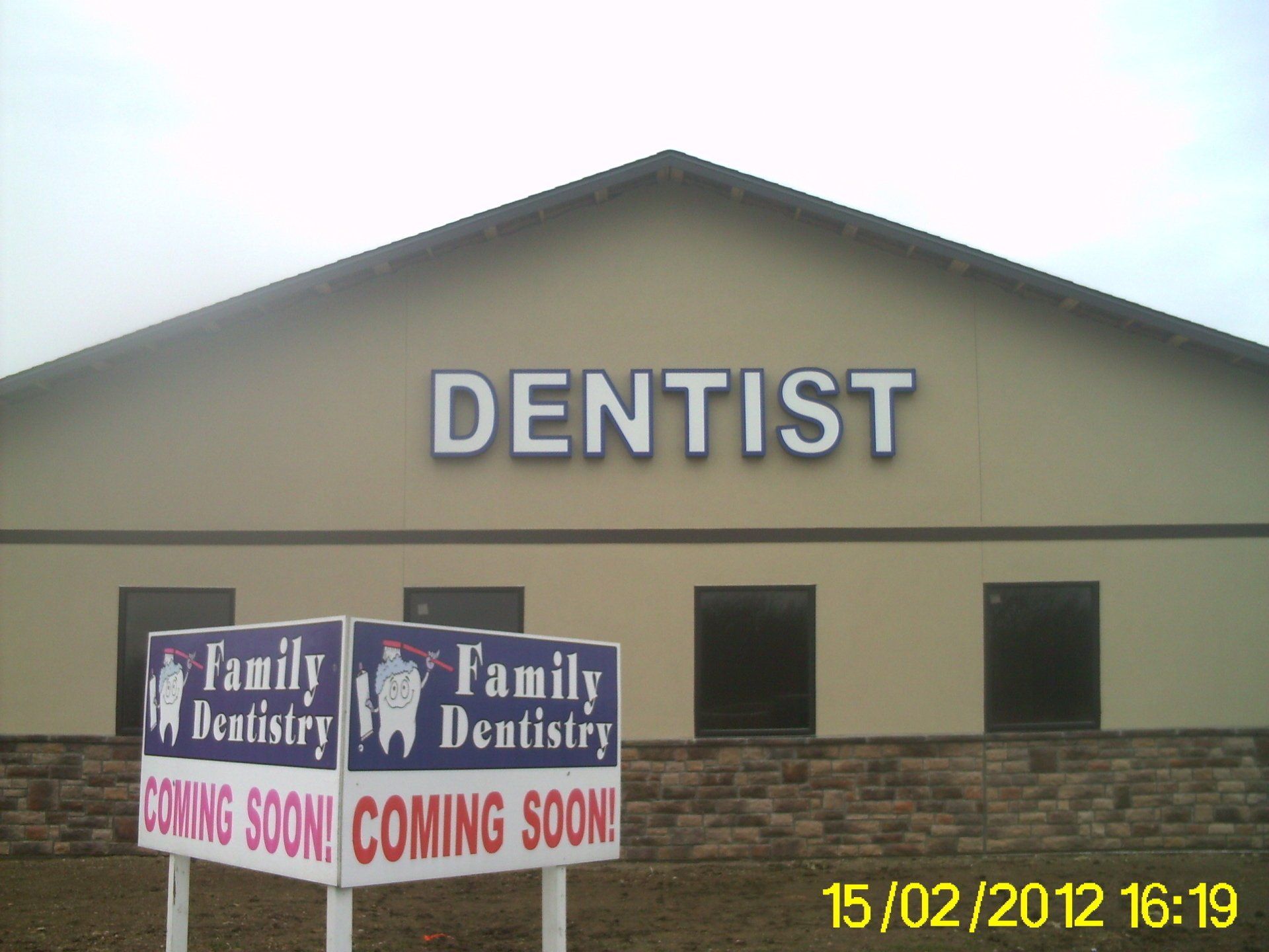 Dentist office exterior with Family Dentists signs and “Coming Soon” banners under a gabled roof