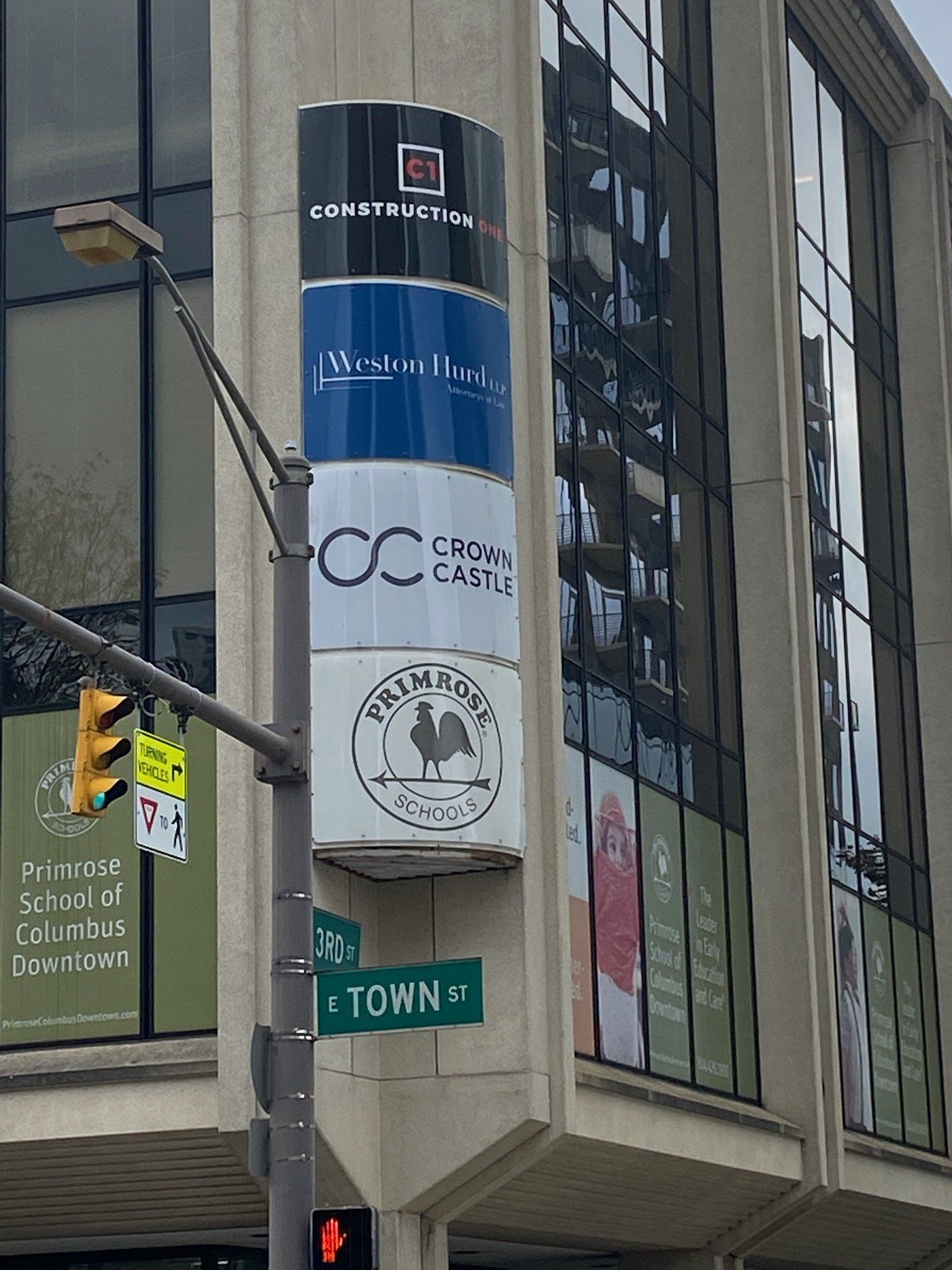 Street corner with tall building signs, traffic lights, and a green TOWN sign.
