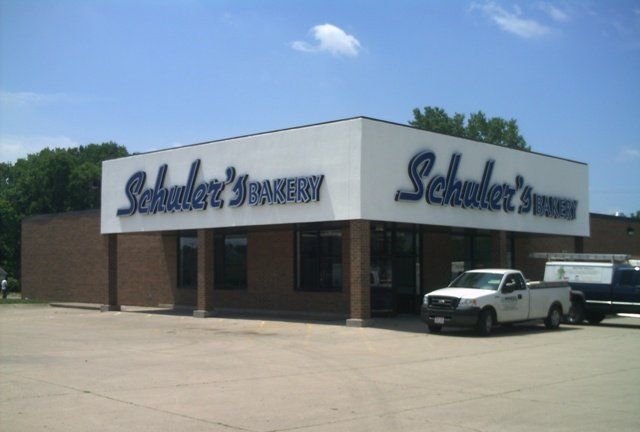 Schlotzsky’s deli storefront with white facade, brown trim, and a parked white pickup truck outside
