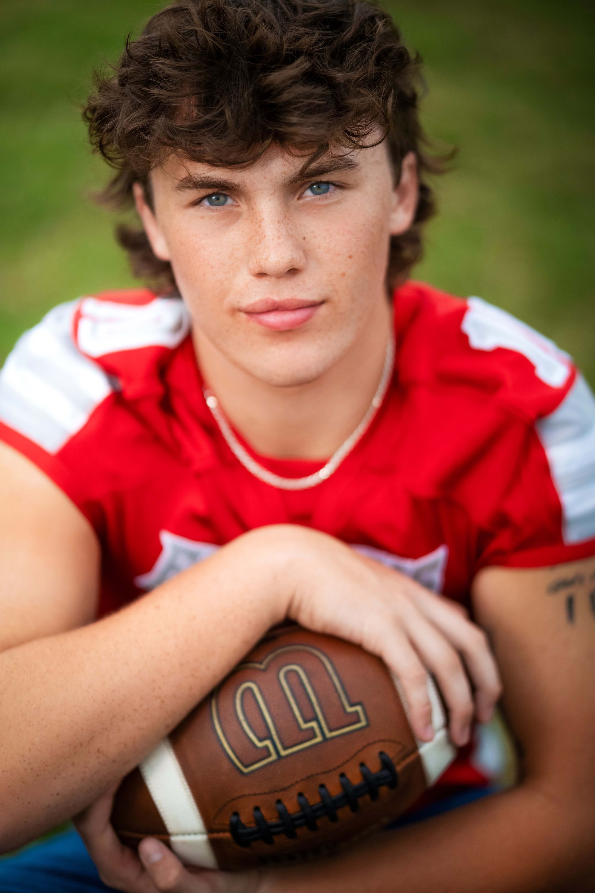 Young man in a red jersey with a football, looking at the camera.