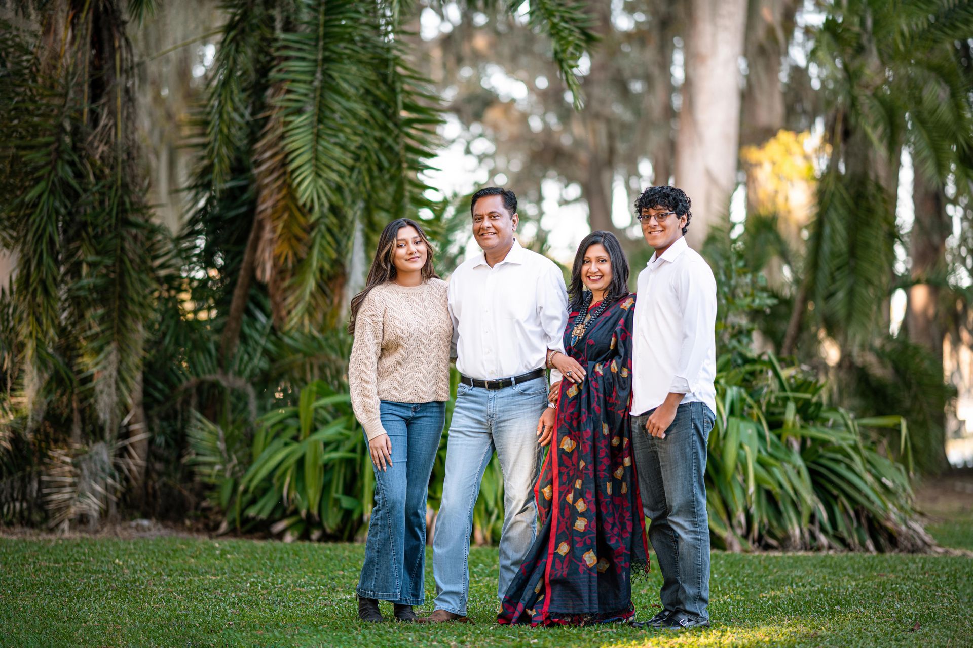 Four people standing together in a lush garden, smiling at the camera.