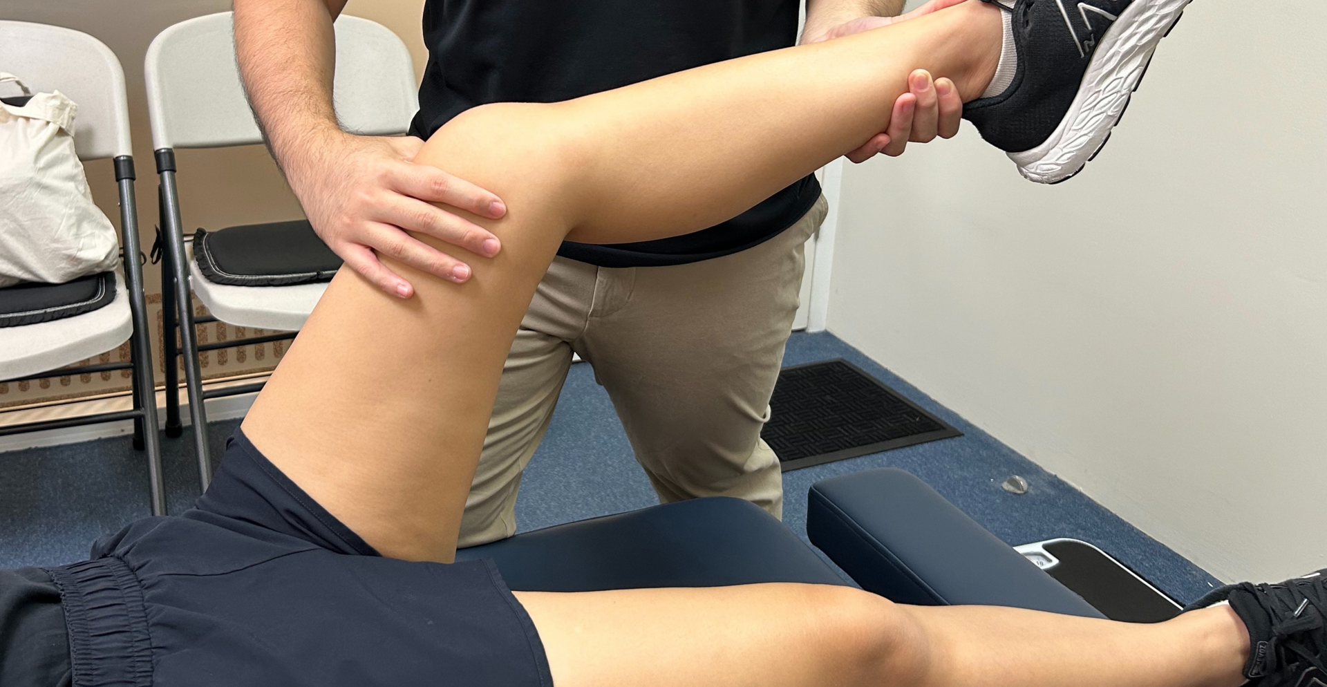 A physical therapist performing a hip range-of-motion assessment on a patient lying on a treatment table.
