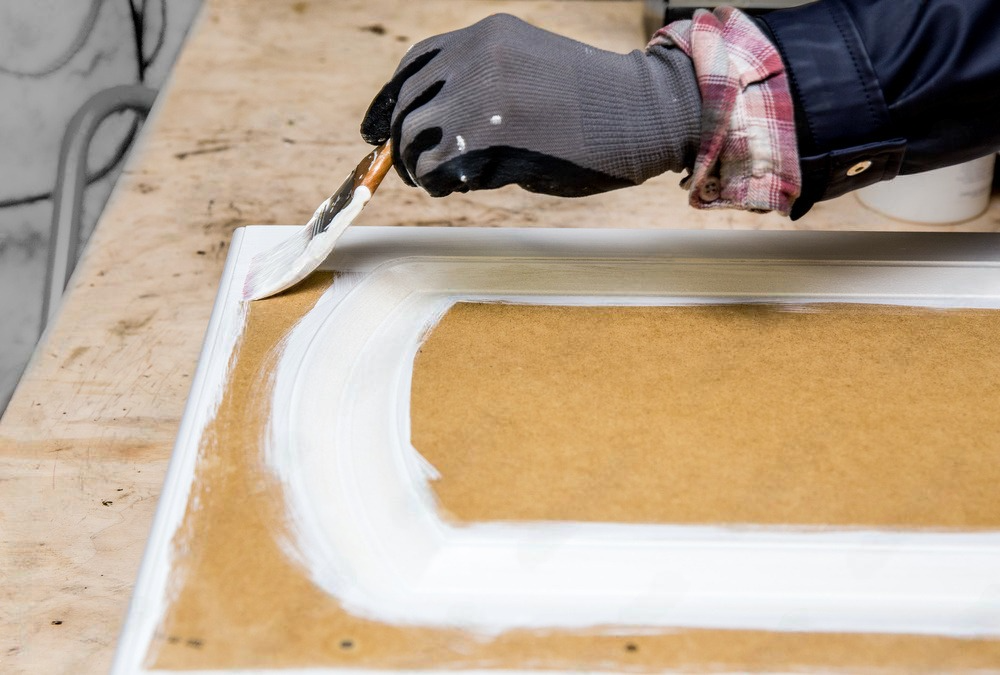 a person is applying glue to a piece of wood .