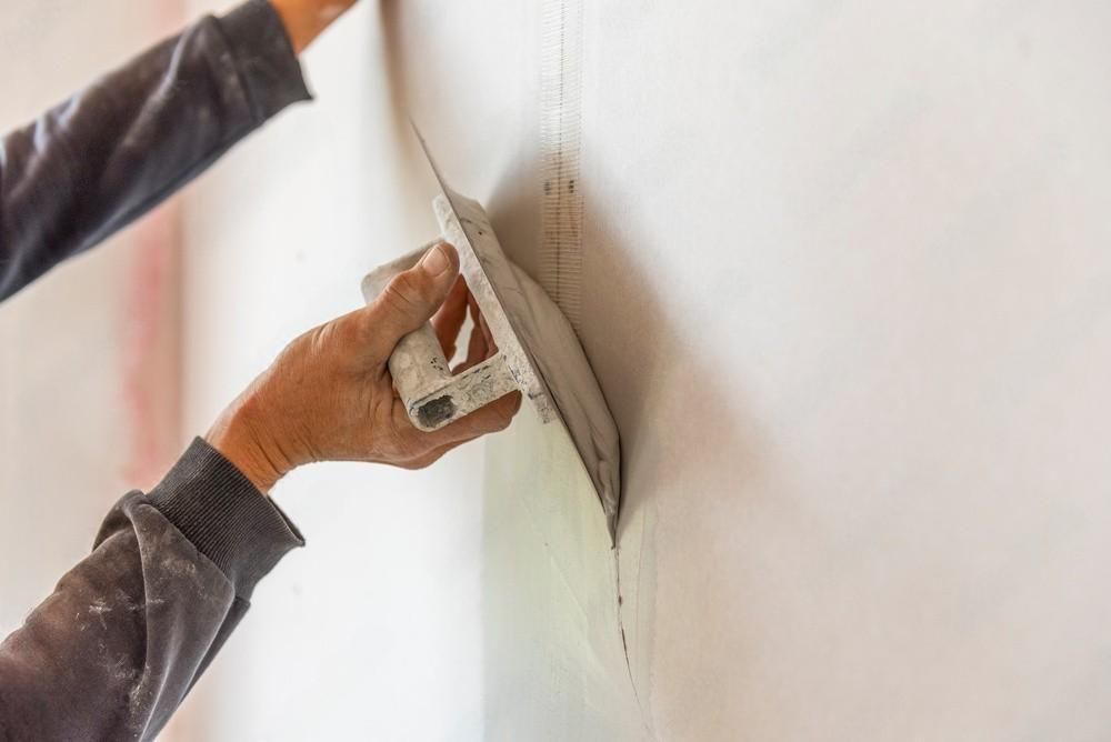 a person is plastering a wall with a trowel .