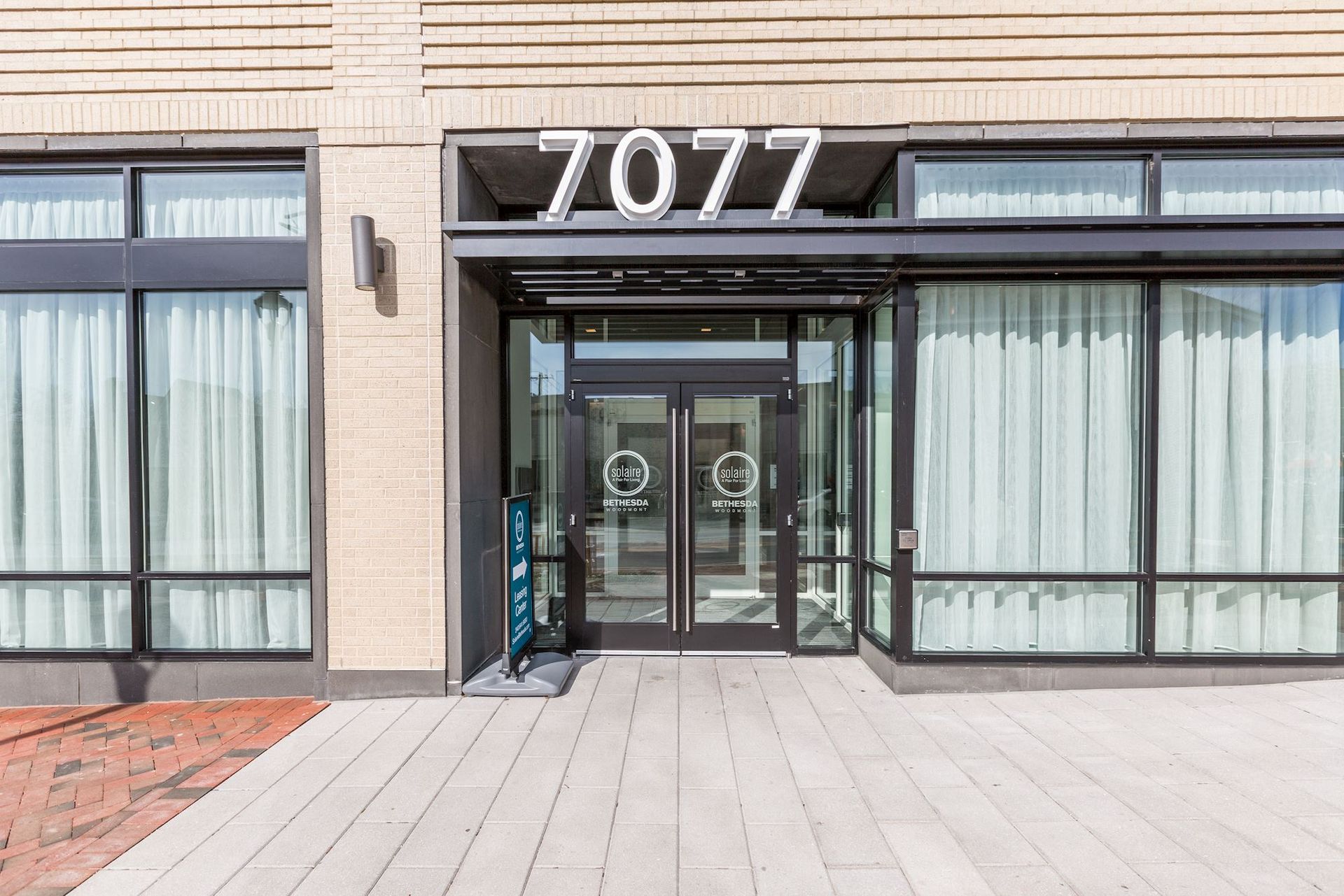 A large building with a lot of windows and a sign that says ' 7777 ' at Solaire 7077 Woodmont in Bethesda, MD.